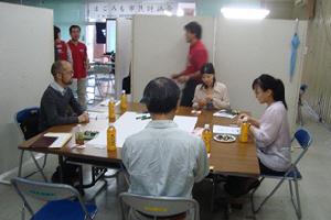 テーブルについて話し合いをしている男性2人と女性2人の写真