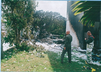 作業着を着た男性二人が火事の現場でトランシーバーを持って話をしている写真