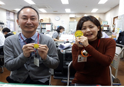 両手で黄色の用紙を持ち、社会福祉協議会の2名の男女の笑顔の写真