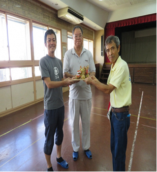 出来上がった作品を一緒に持っている3人の男性の写真