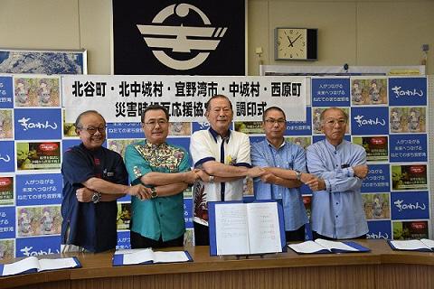 北谷町長、北中城村長、宜野湾市長、中城村長、西原町長全員で腕を組んで記念撮影