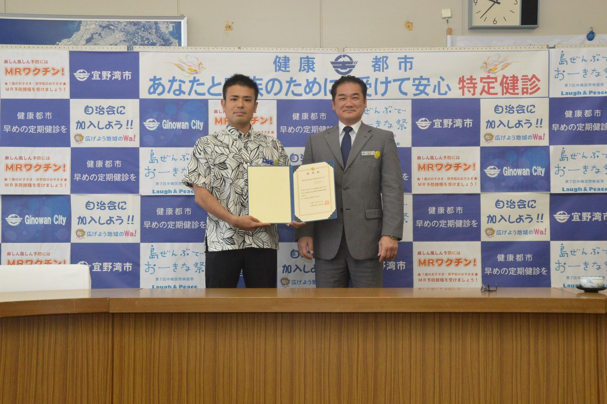 自主防災組織認定式にて大山区自治会長が認定書を手に市長と記念撮影している写真