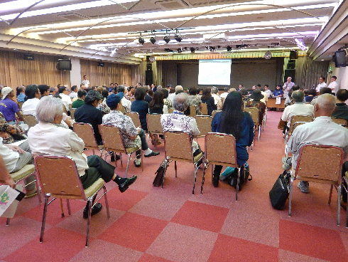 説明会に参加された方々が椅子に座って話を聞いている様子を後ろから写した写真