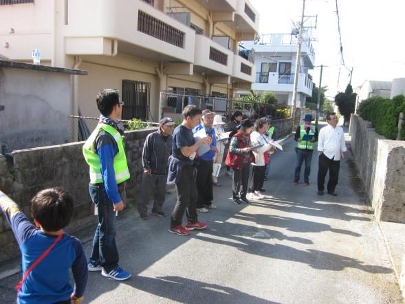 反射ベストを着た方や資料を持って話を聞いている方と子供が指を指している写真