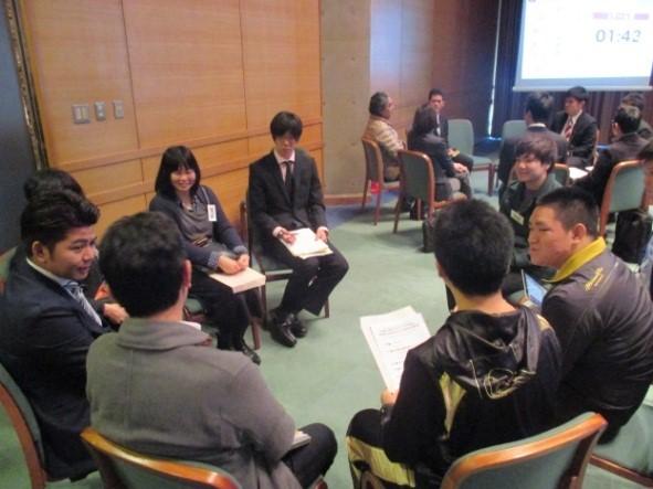 椅子に座り、資料を膝の上に置き円になって話をしている写真