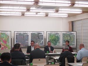 ホワイトボードにおおきな地図が貼ってあり、前に職員が座っていて、参加された方々が座っている後方から見た写真