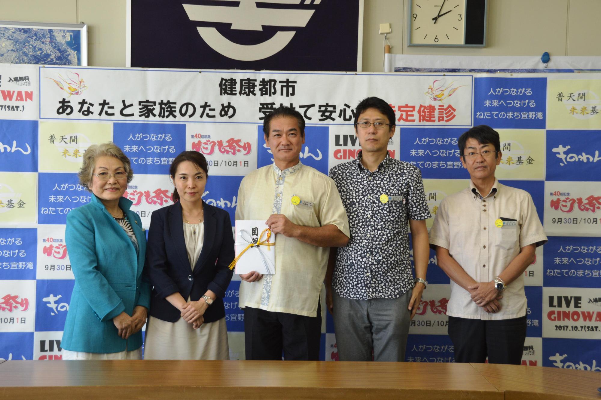 目録を持っている佐喜眞市長と関係者の方々の写真