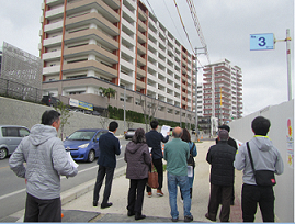 マンションが立ち並ぶ街並みを見ている方々の写真