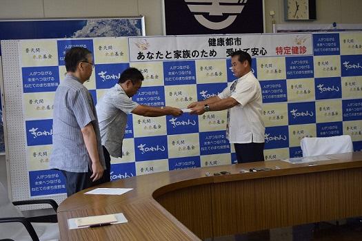 2名の男性が並び内1名が市長へ抗議・要請文書を手渡している写真
