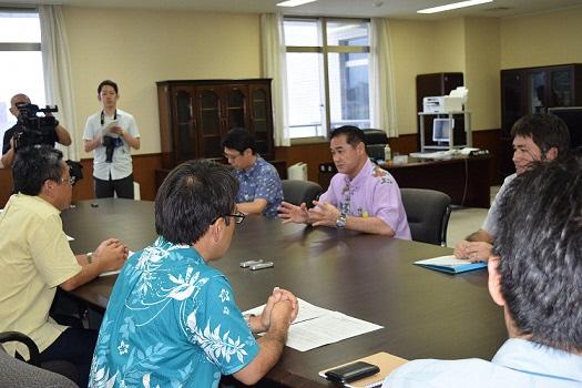 テレビカメラも入り関係者らが向かい合って席に座り話し合いをしている写真