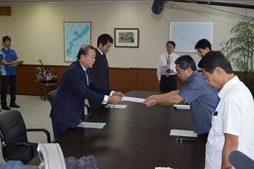 関係者5名が向かい合って立ち抗議・要請を手渡している写真