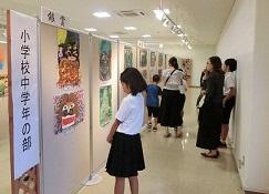 小学校の部、中学校の部の絵画を見学している子供や大人の写真