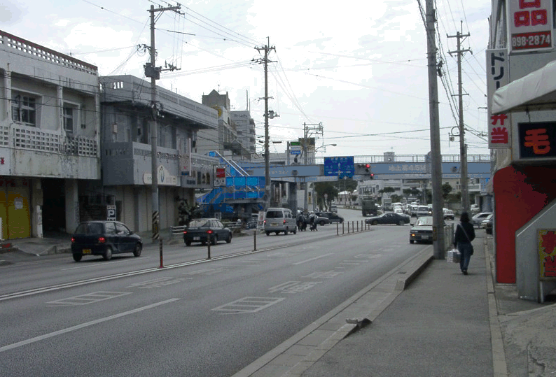車の走っている道路の奥に歩道橋が見えている写真