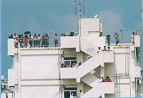 白い建物の屋上や外付けの階段に見物人が集まっている写真