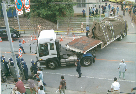 機動隊が出動し規制線が貼られた現場からトラックに乗せて落下物を運んでいる写真