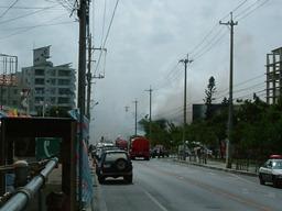 道路には消防車や救急車が停まっていて奥の方で煙が上がっている写真