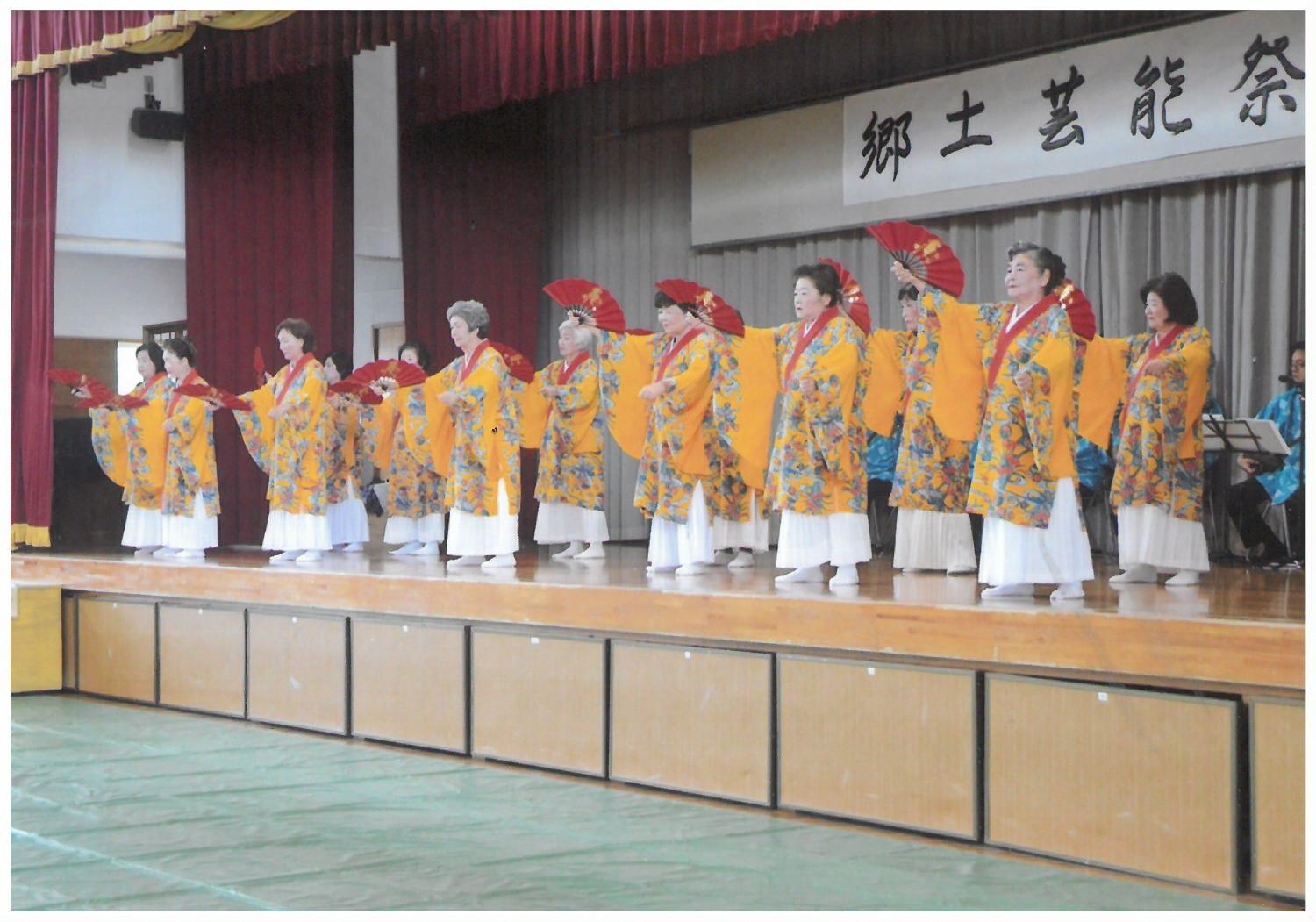 沖縄の伝統衣装を着て扇子を持ち踊りを披露している女性のグループの写真