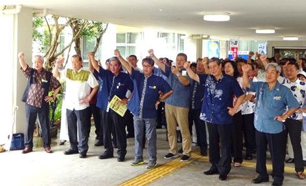 市役所玄関前で参加者全員が右手を上げて気合いを入れている写真