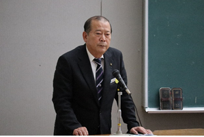 演壇の上に両手を置きマイクの前で話をしている松川市長の写真