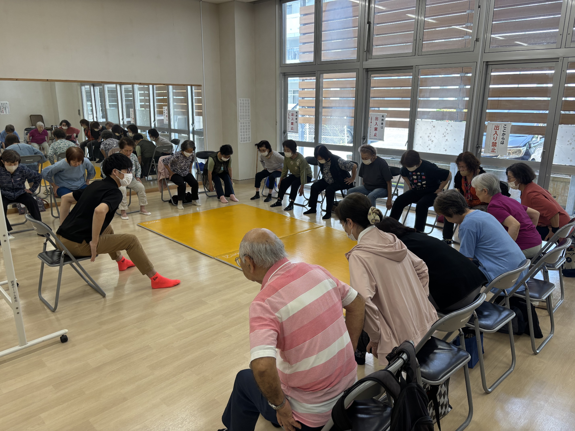 がんじゅう広場。指導者が動作法についてお話している。参加者は円になってお話を聞いている。