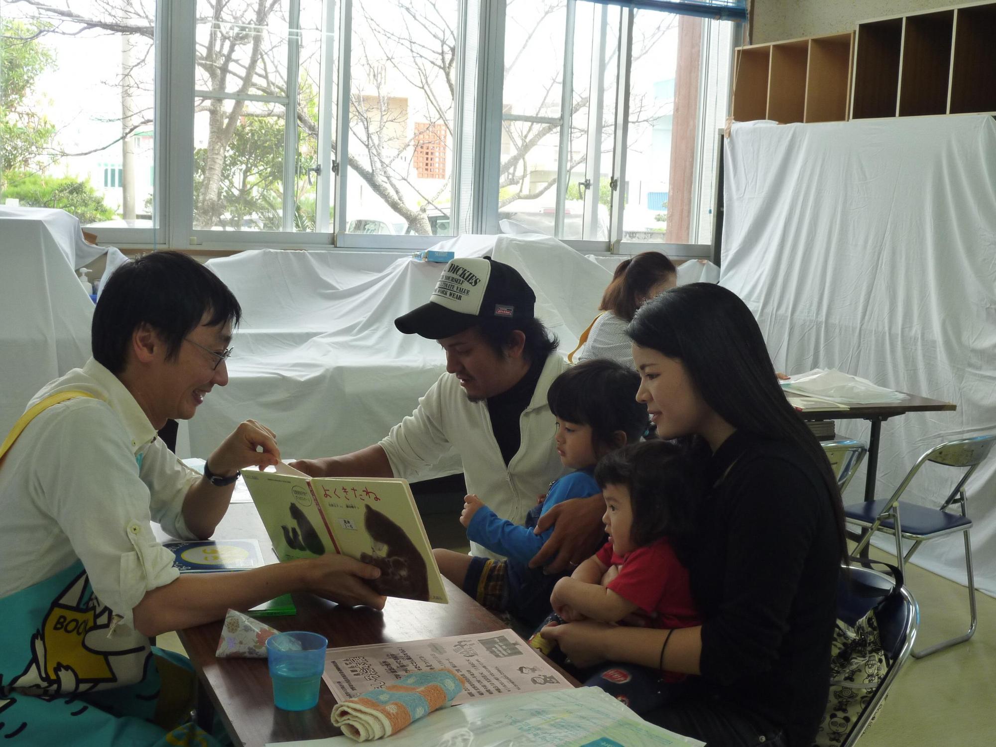 ボランティアの方が赤ちゃんに絵本の読み聞かせを行っている様子の写真