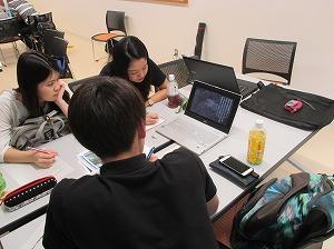 ノートパソコンを使い、視聴しながら鉛筆をとる大学生3人の写真