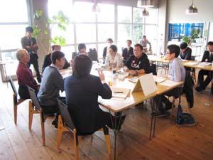 15名ほどの参加者がカフェにて机を囲みディスカッションをしている写真