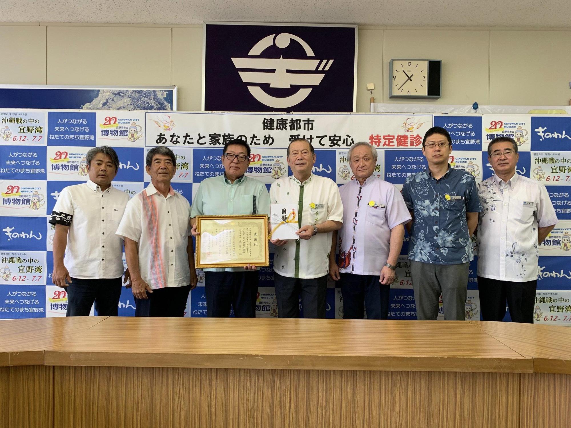 目録を持っている松川市長と額縁に入った賞状を持っている男性の横に5名の関係者の方々が写っている集合写真
