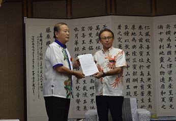 市長と沖縄県知事が一緒に胸の高さで書類を持っている写真