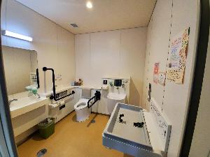 手すり、おむつ交換台、オスメイト対応トイレなどが取り付けられている多目的トイレ内の写真