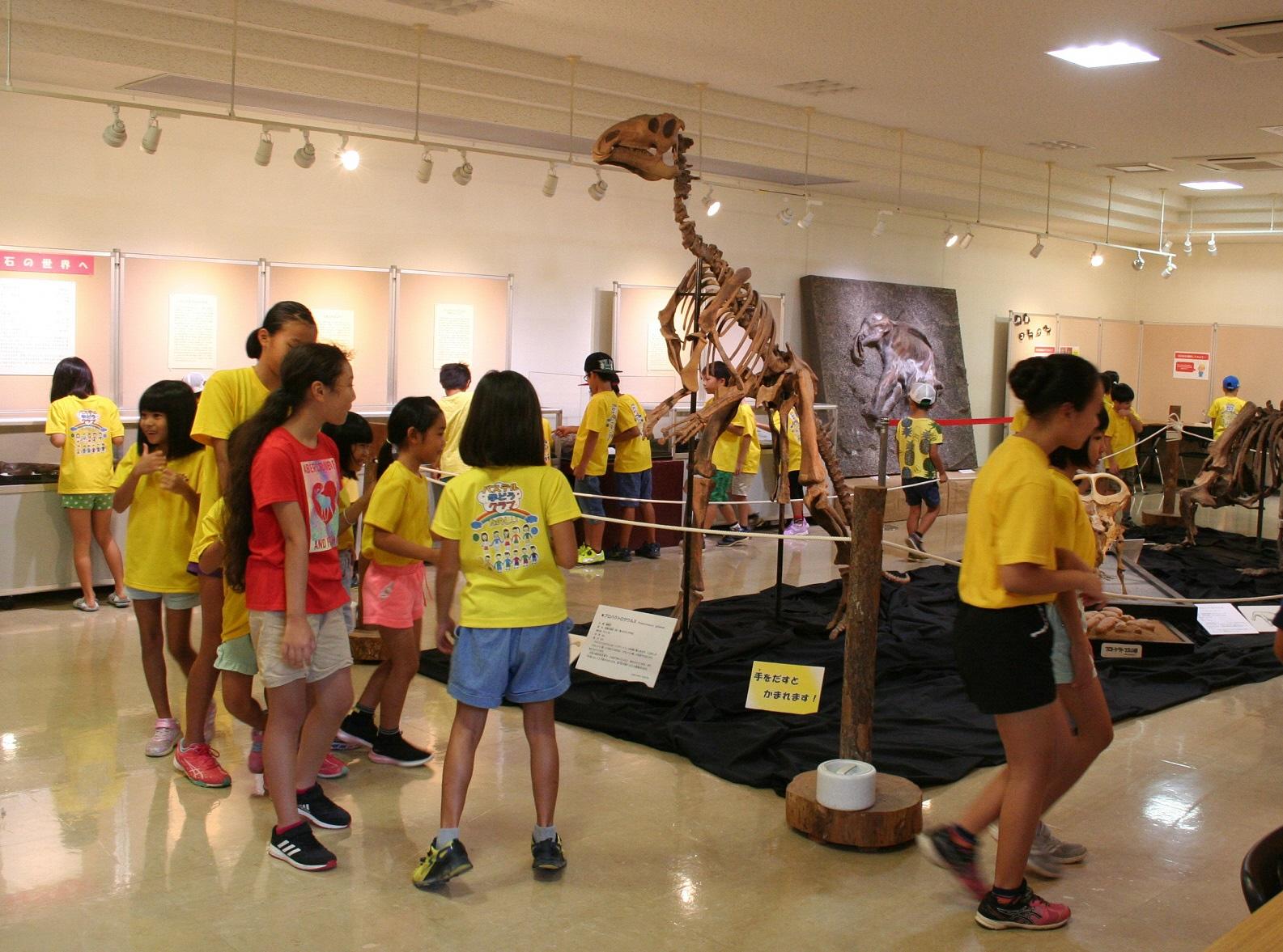 恐竜の化石の展示の周りを子供たちが見学している写真