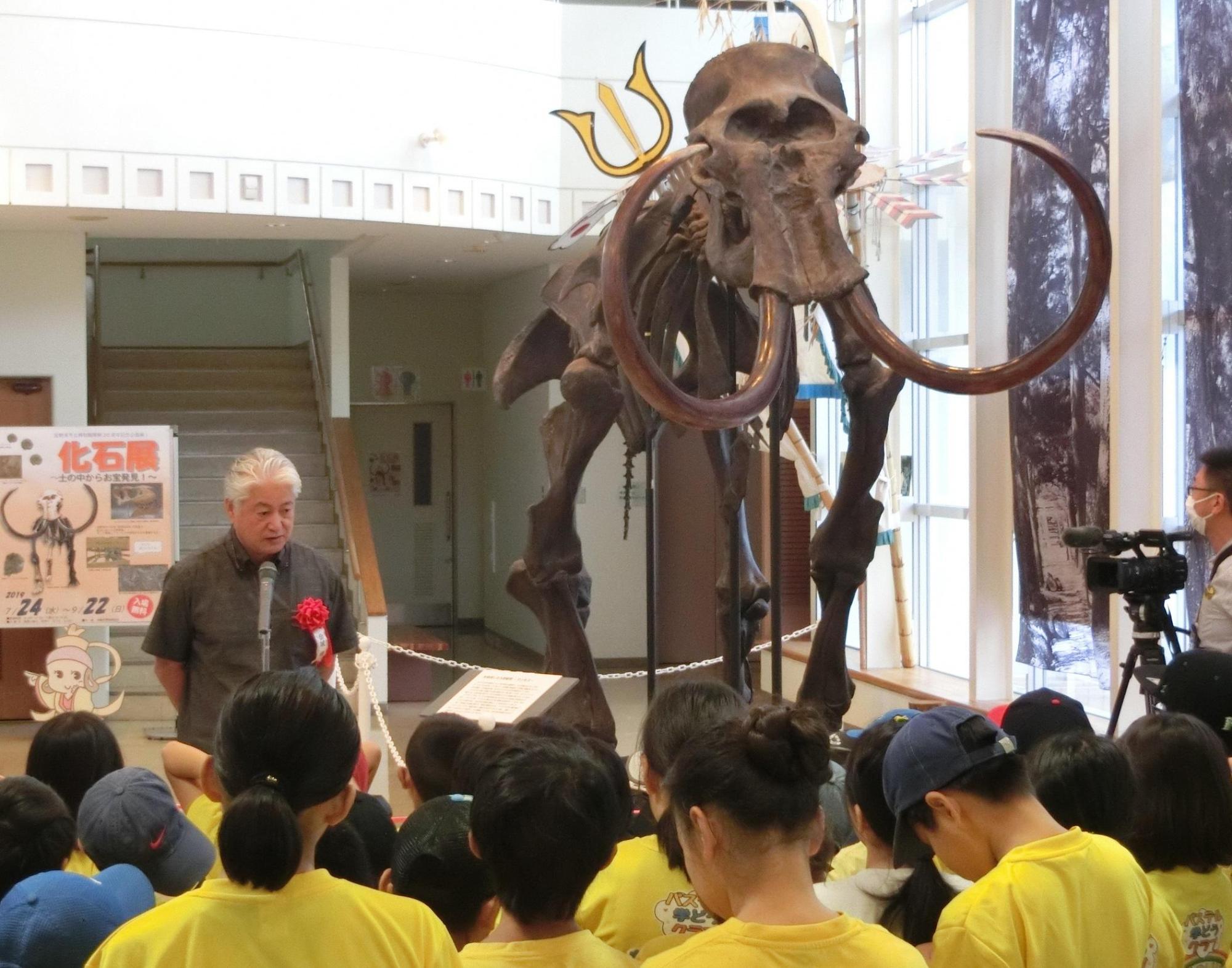 沖縄県立博物館・美術館金城 健副館長が子供たちの前で挨拶をしている写真