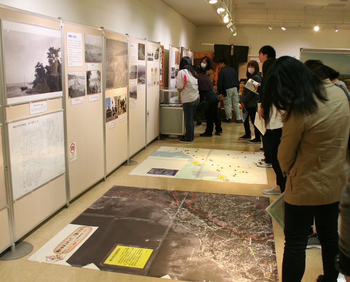 展示室の床に貼られた2枚の地図を見学をしている来場者の写真