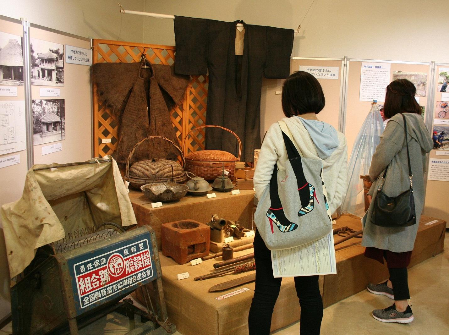 古い袴の衣装や調理道具などの展示品を見学している来場者の写真