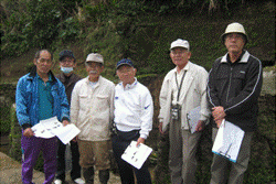 軽便鉄道「真志喜駅」跡近く前に6名で資料を片手に並んで記念撮影をしている写真