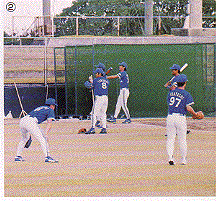 青色のユニフォームに帽子を被った選手たちが野球の練習をしている写真